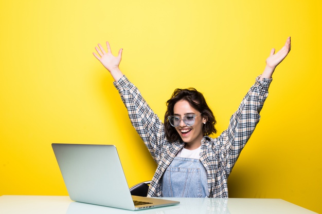 cheerful-pretty-woman-glasses-holding-laptop-showing-fist-up-excited-with-win_231208-5619